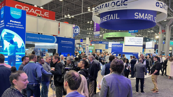 Lots of business people walking around a trade show floor with technology booths